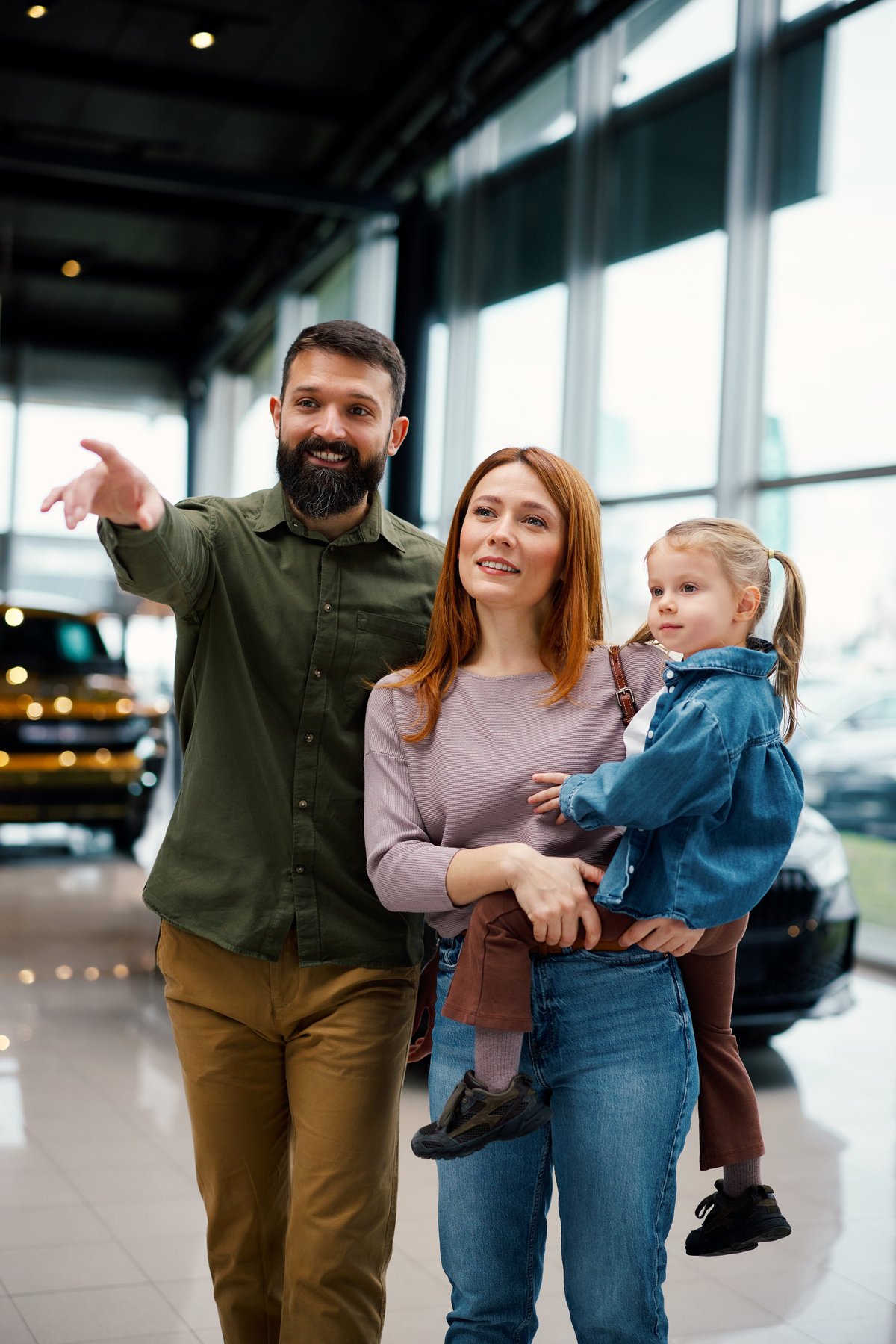 Parents with daughter choosing new car in showroom